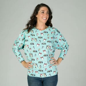 Dark haired lady with hands on hips wearing ice blue penguin top