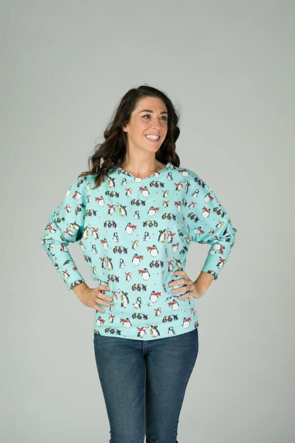 Dark haired lady with hands on hips wearing ice blue penguin top